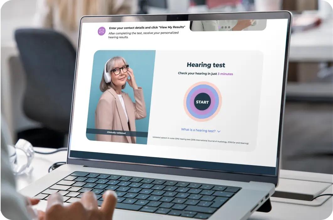 Laptop on a table showing the Lexie Hearing free online hearing test on the screen.