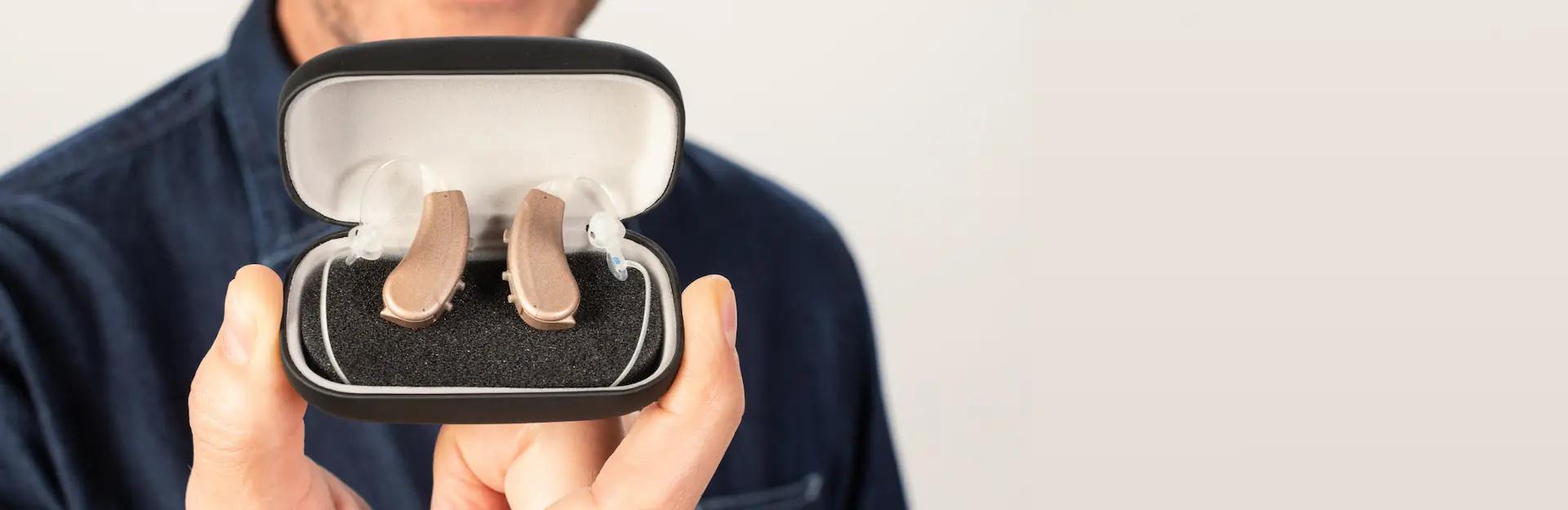 A person holding the Lexie Lumen hearing aids