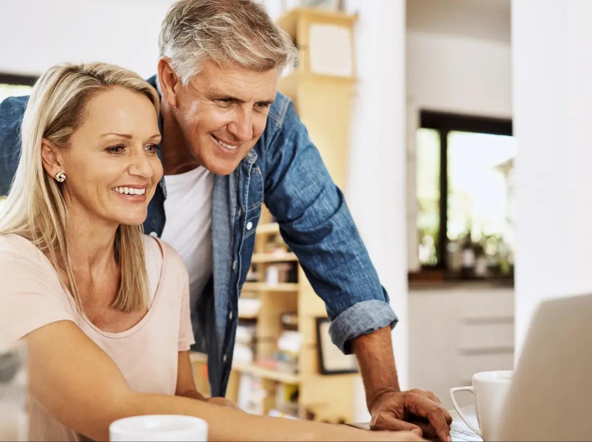 A couple smiling and looking at a laptop