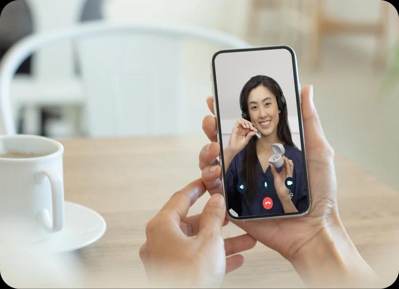 Hand holding a phone speaking with a Lexie Expert over video call.