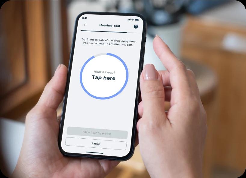 Hands holding a phone with the in-app hearing test screen running