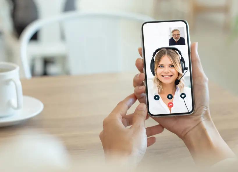 Hand holding a phone speaking with a female Lexie Expert over video call.