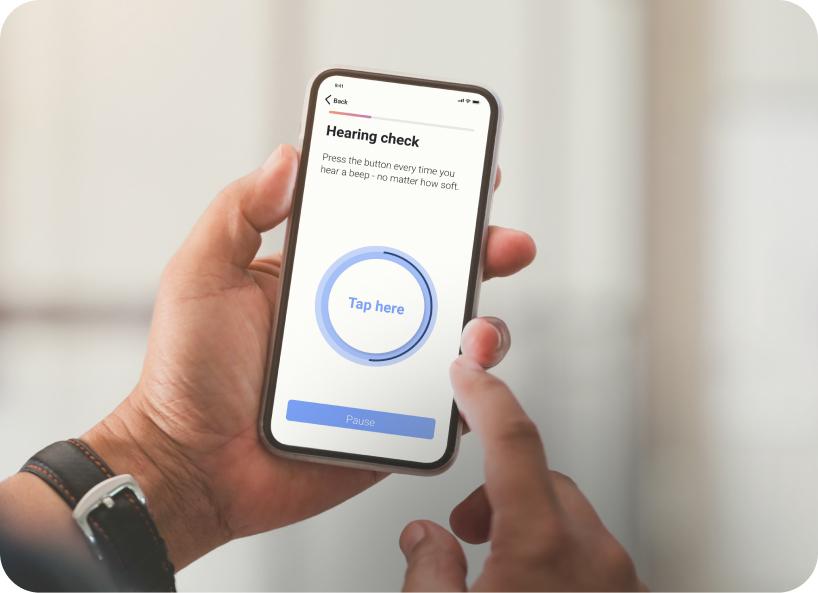 Hand holding a phone testing Lexie Lumen hearing aids through the hearing check on the Lexie app.