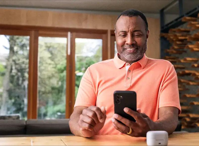 A man smiling and looking at his phone.