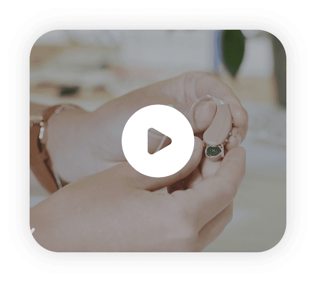 A hand holding a Lexie Hearing Aid product. Click to play the video.