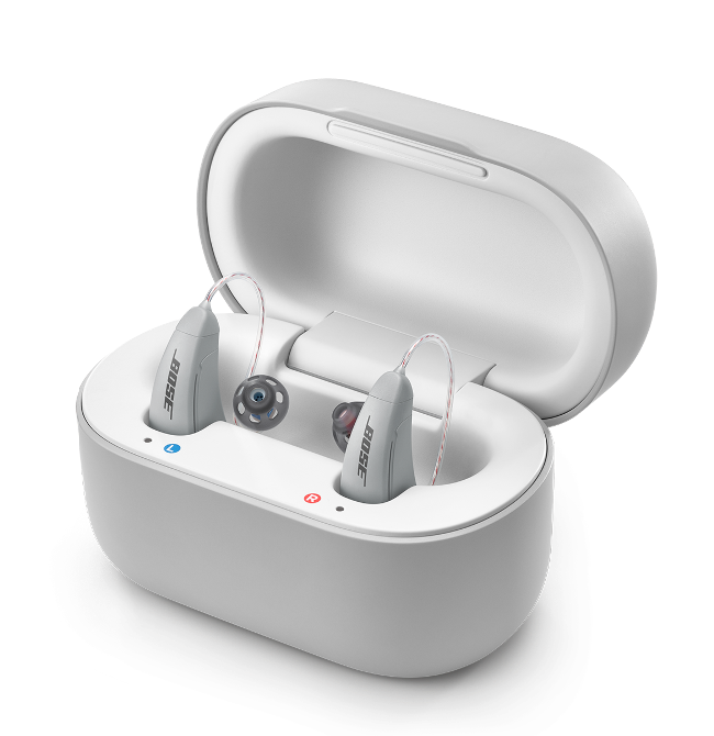 A pair of gray Lexie B2 Powered by Bose hearing aids, inside of a gray case.