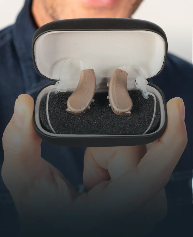 A person holding the Lexie Lumen hearing aids