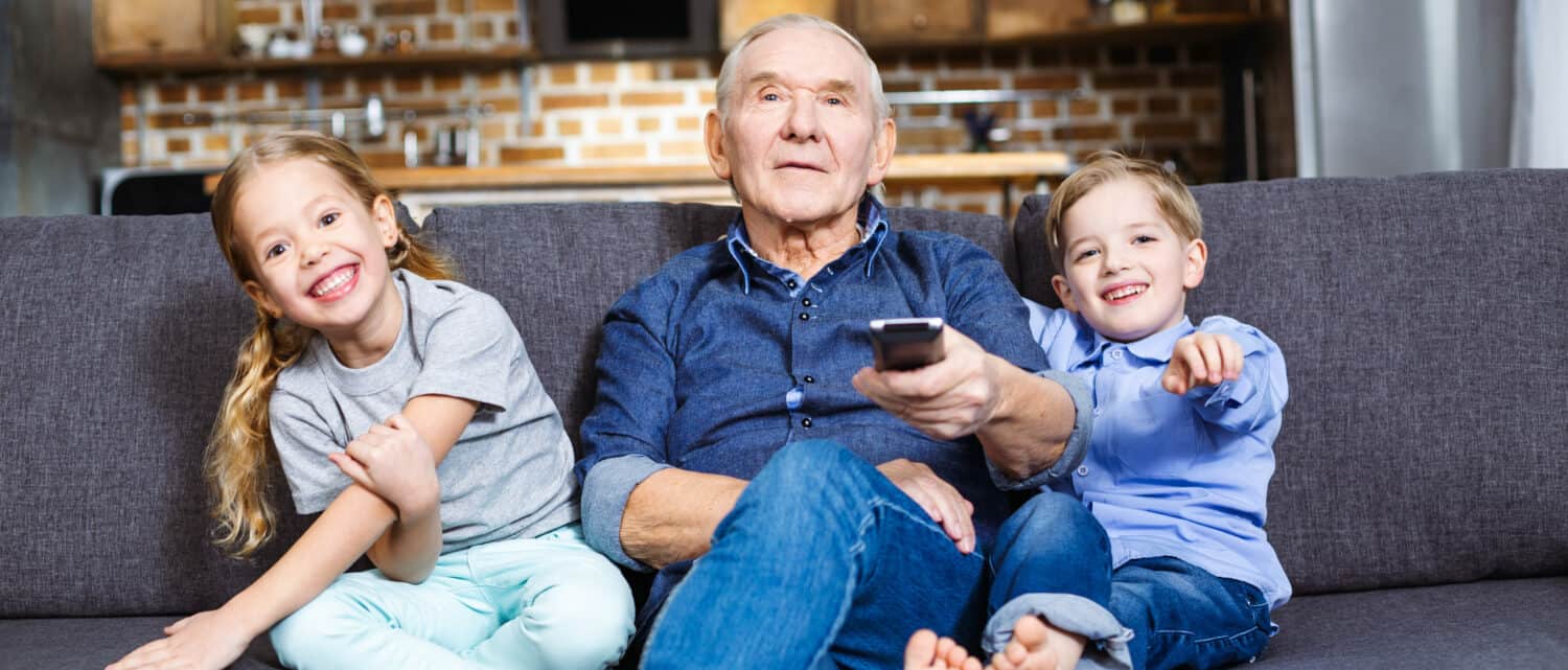 Man using a hearing aid companion microphone while watching television with his grandkids
