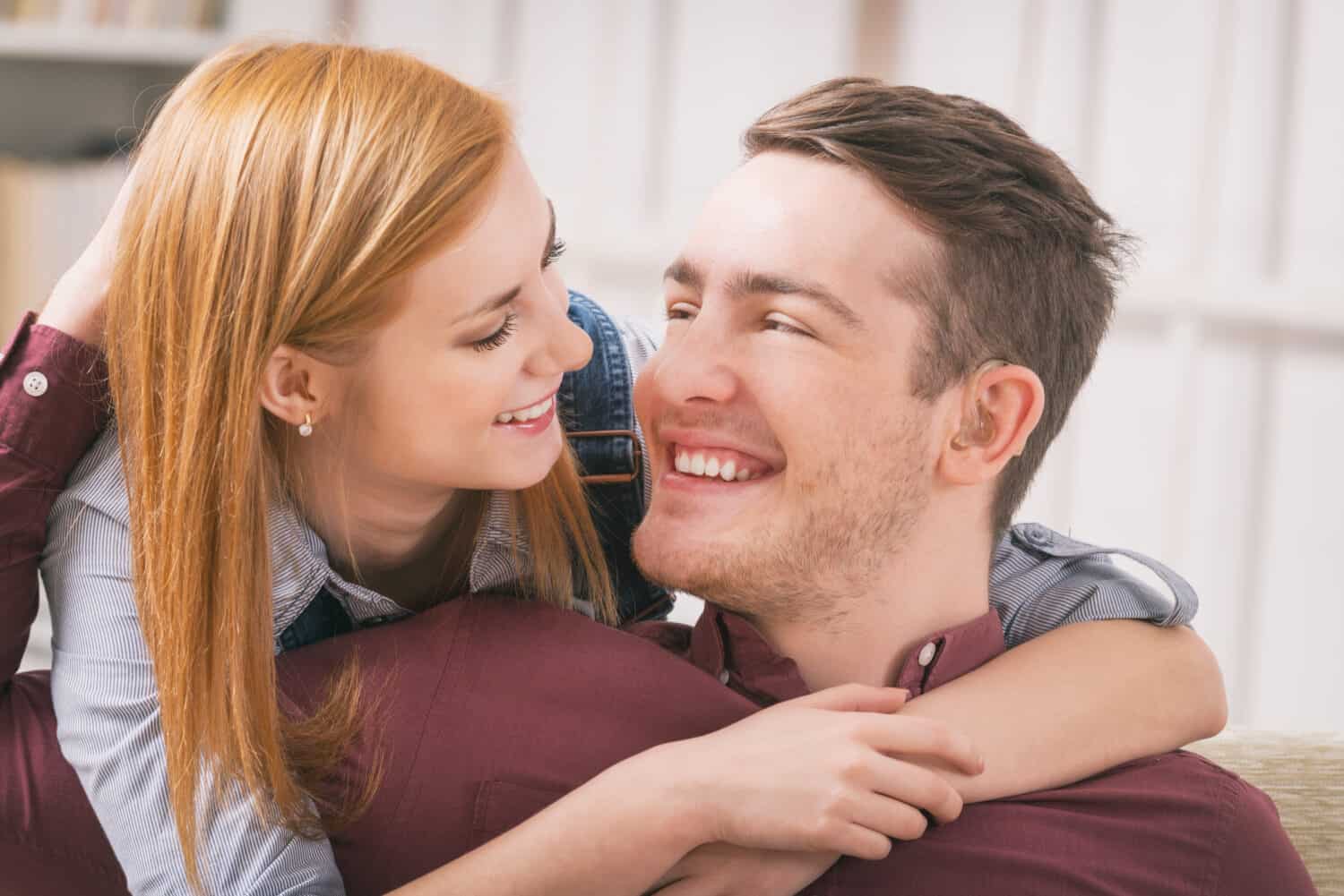 Young woman hugging a man with hearing aids