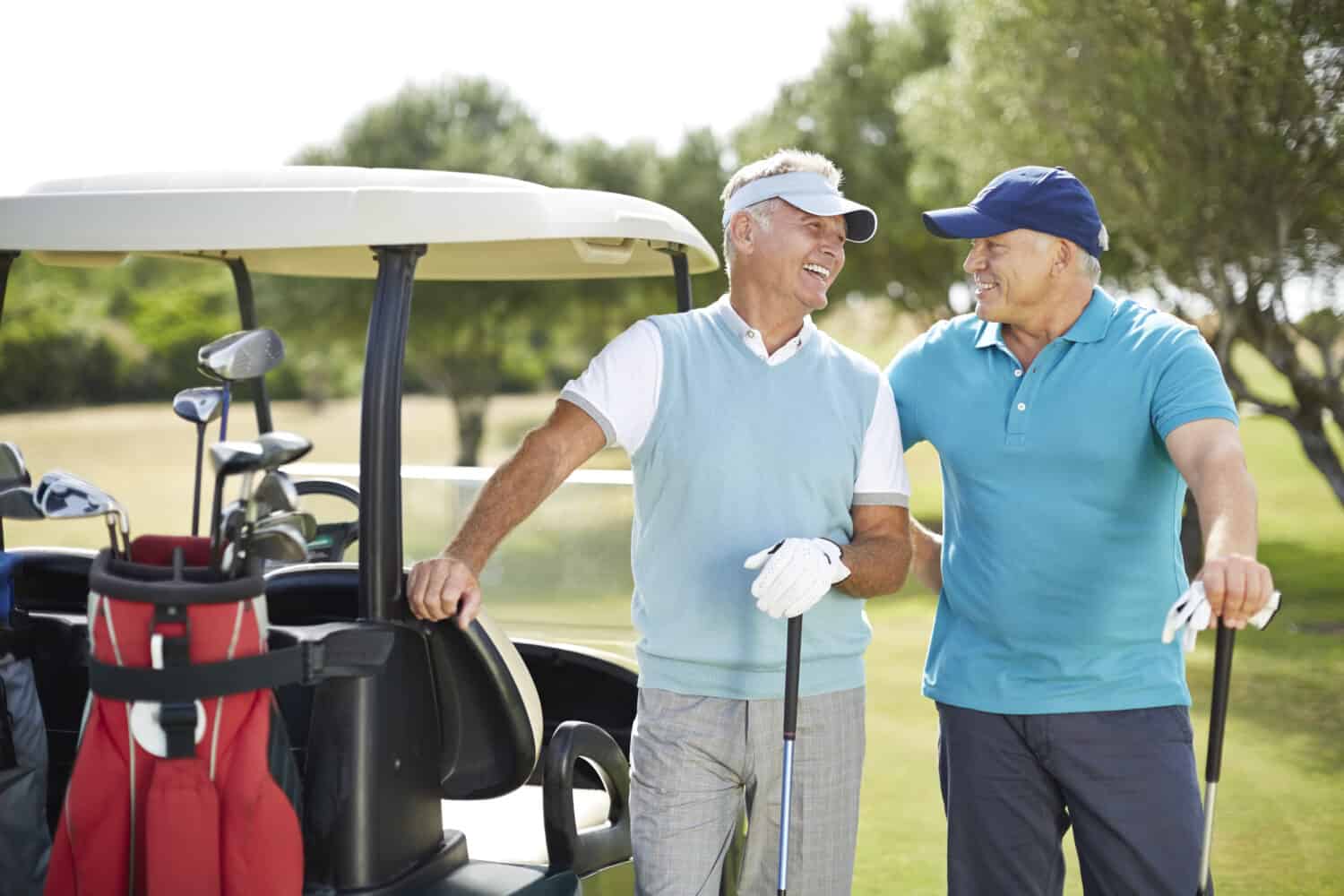 Two men wearing premium hearing aids outside while playing golf