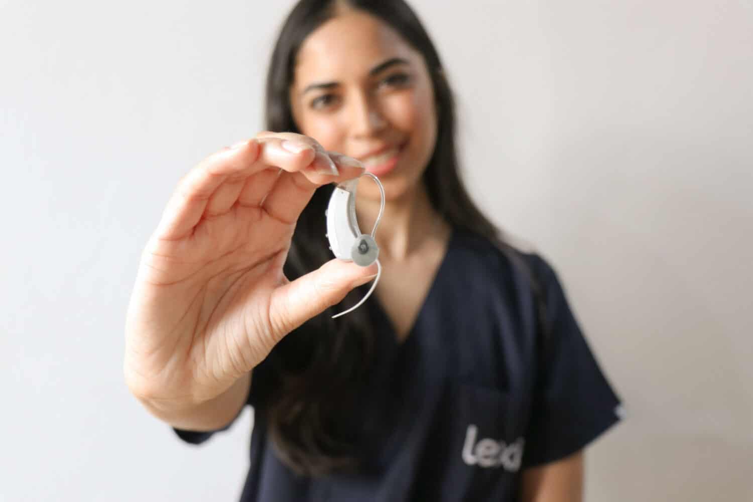 Lexie hearing expert holding a Lexie Lumen hearing aid