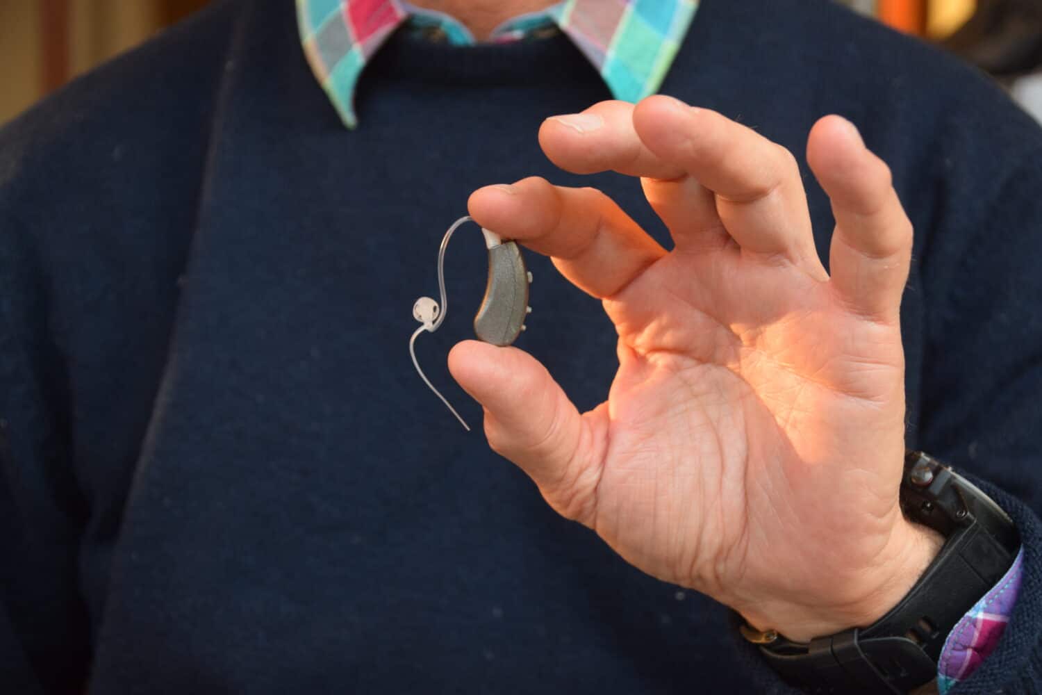 Man holding the Lexie Lumen hearing aid