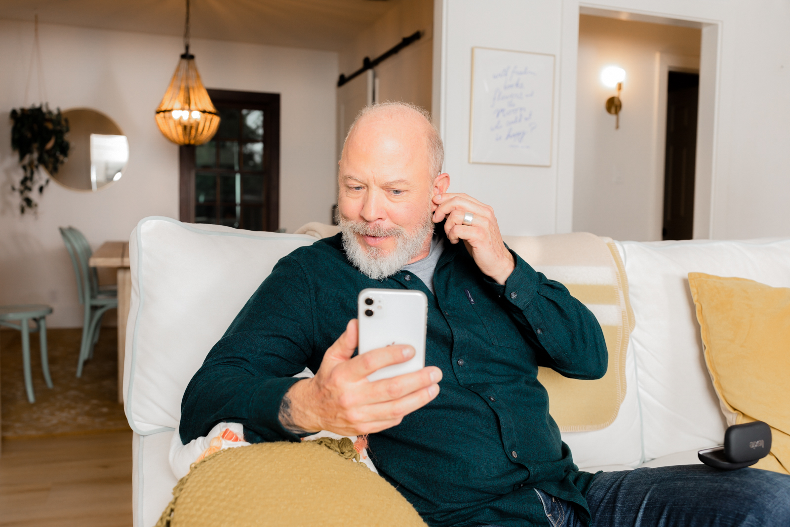 Man inserting his hearing aid while receiving follow-up care over the phone