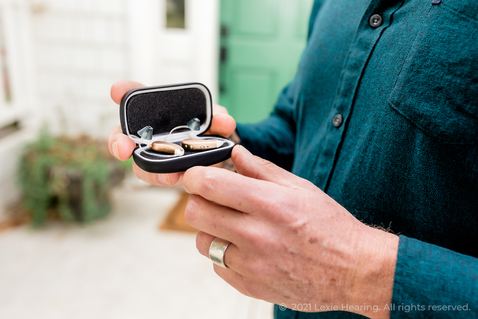 Man holding the Lexie Lumen hearing aids in their Lexie box. The Lexie Lumens are battery hearing aids that are high quality and affordable