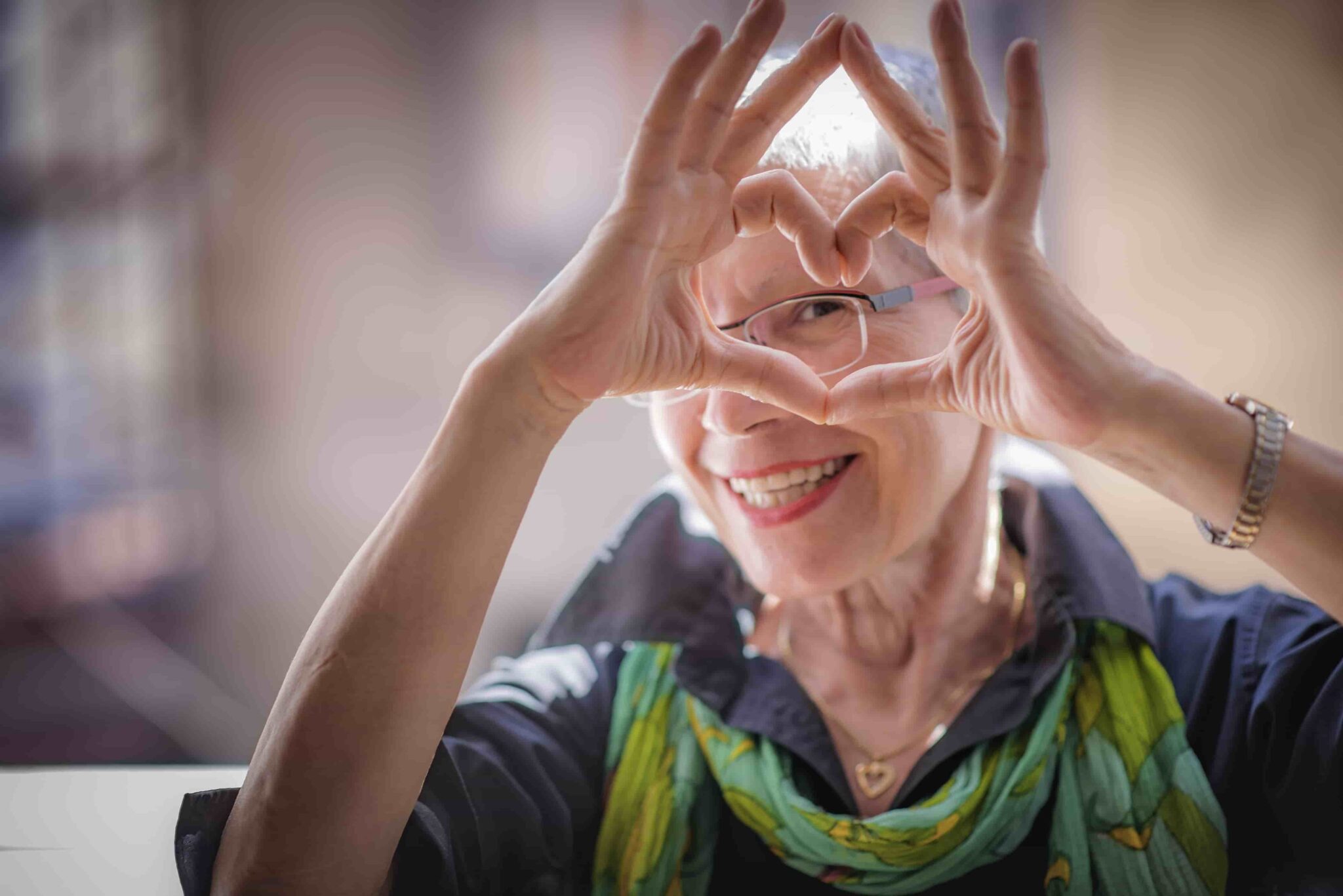 Senior woman making a heart shape with her hands after learning what to do with her old hearing aids
