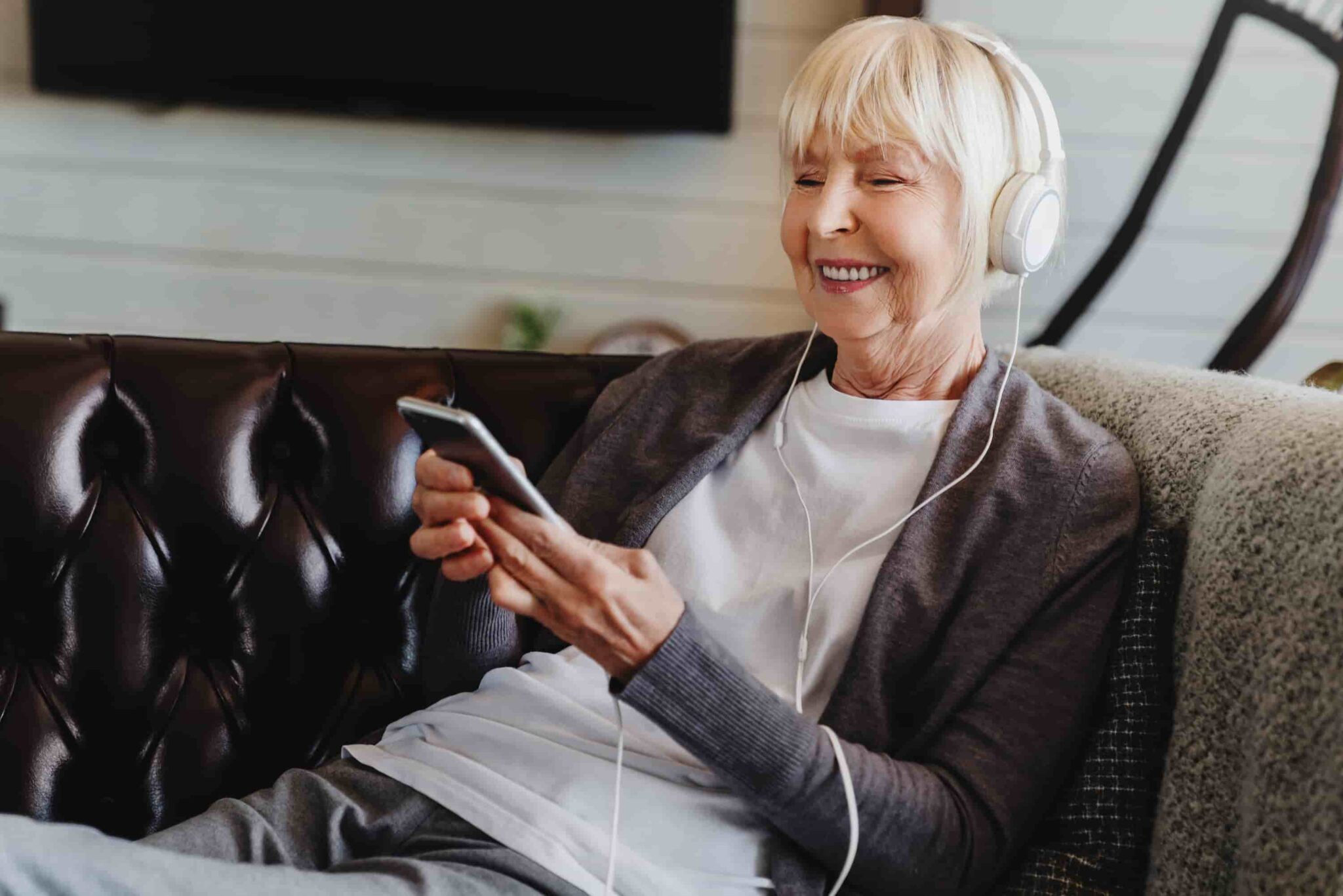 Senoir woman on the couch with headphones. Headphones and hearing loss