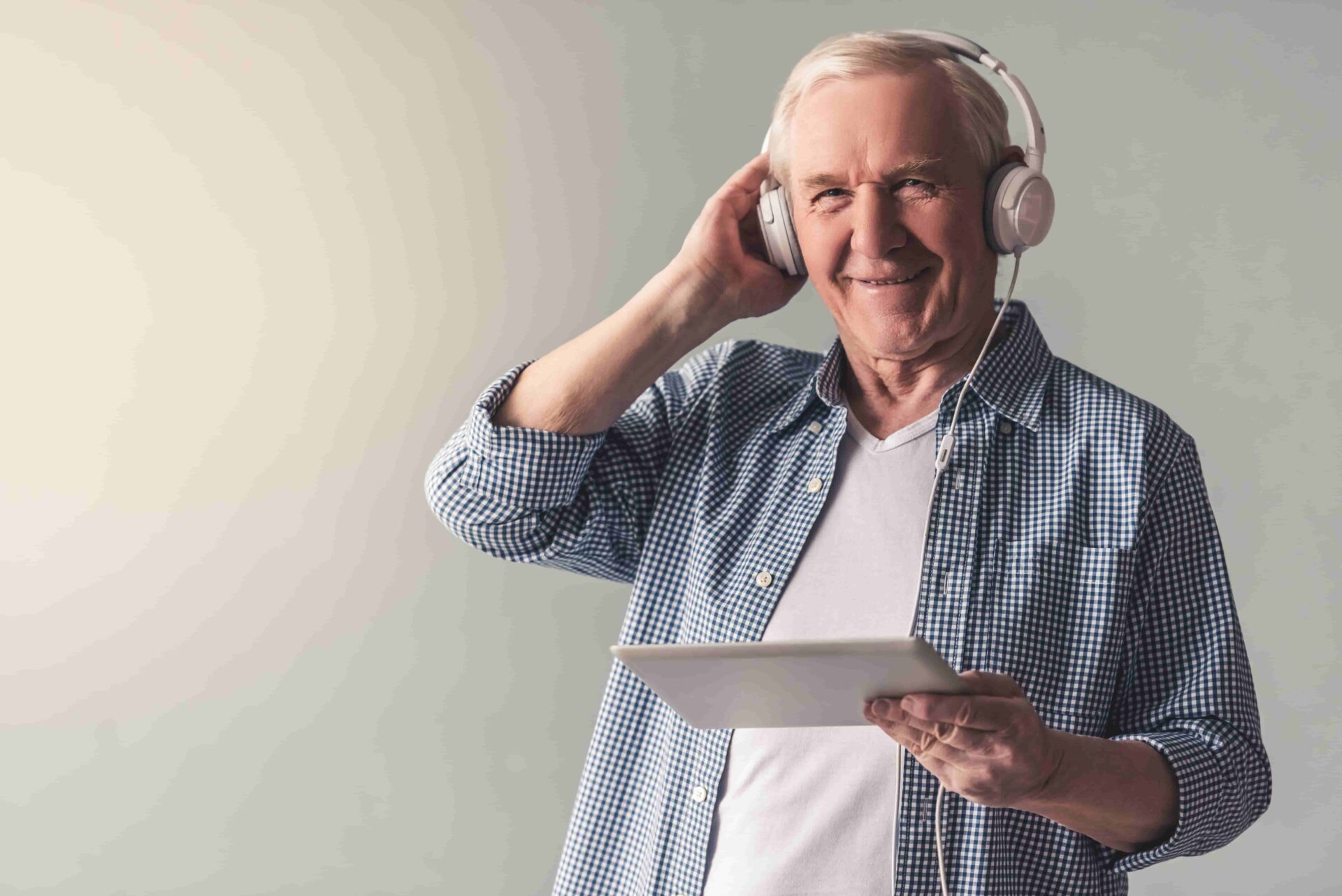 Senior man wearing headphones and holding an iPad