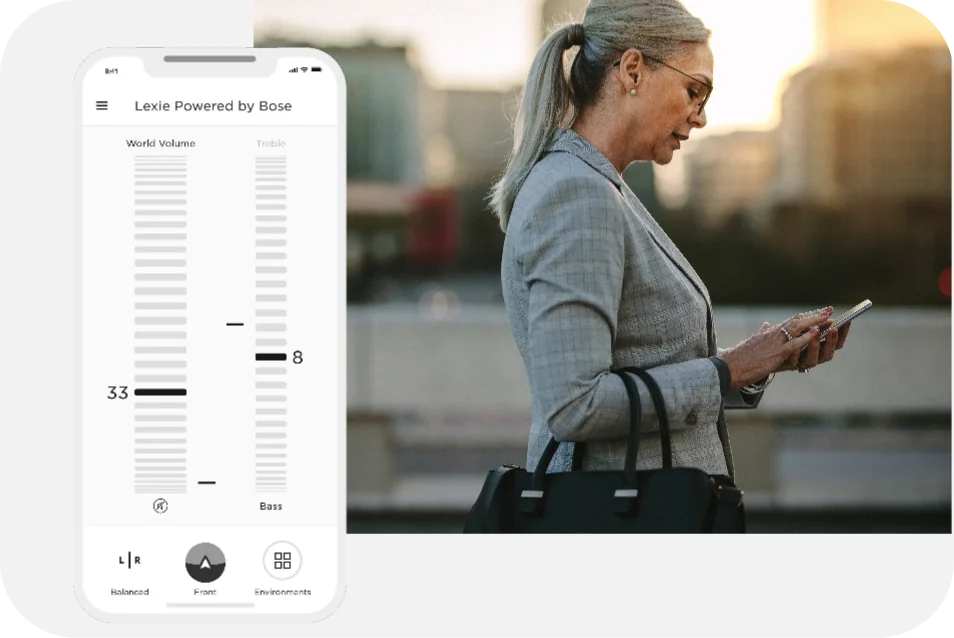 A screenshot of the Lexie Hearing App's home page. To the right is a woman, in suite, looking at her phone.