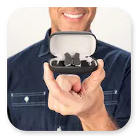 Lexie Lumen Lifestyle | Man holding metallic black Lexie Lumen hearing aids thumbnail.